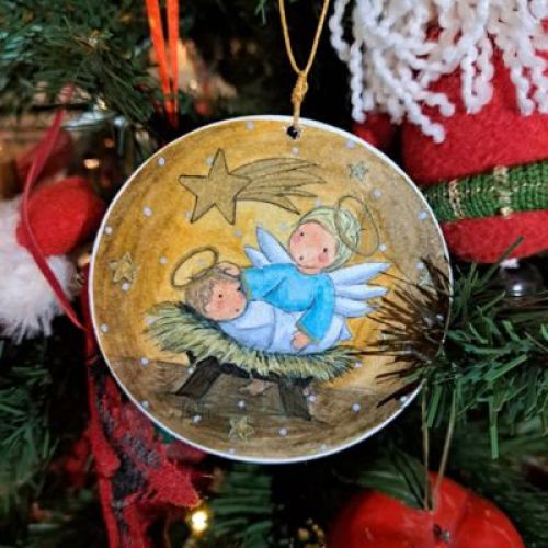 Adorno navideño redondo con ilustración de ángel y Niño Jesús en el pesebre.