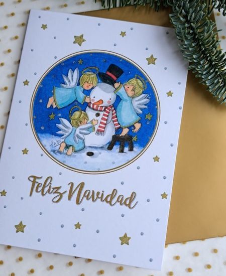 Tarjeta de Navidad con ángeles jugando con muñeco de nieve y mensaje Feliz Navidad