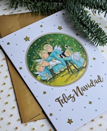 Tarjeta navideña con ángeles adorando al Niño Jesús y mensaje Feliz Navidad