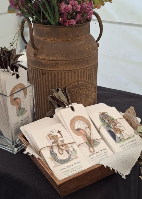 Recordatorios de Primera Comunión con ilustraciones religiosas y la Virgen María, presentados en expositor y bandeja de madera, listos para entregar.